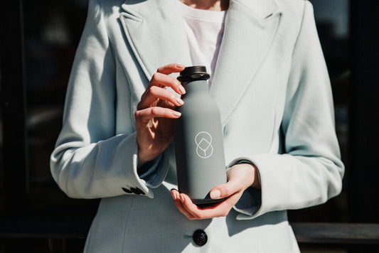 An employee holds a gray water bottle featuring a company logo   
